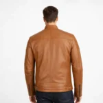 Rear view of tan brown leather biker jacket showing quilted shoulder panels, center back seam, tapered waist design, and ribbed hem detail