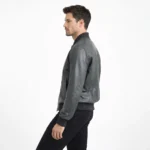 Side profile view of man in gray leather bomber jacket showing relaxed fit ribbed hem and sleeve construction