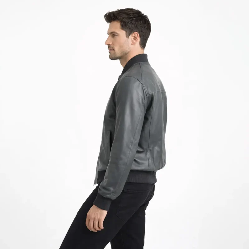 Side profile view of man in gray leather bomber jacket showing relaxed fit ribbed hem and sleeve construction