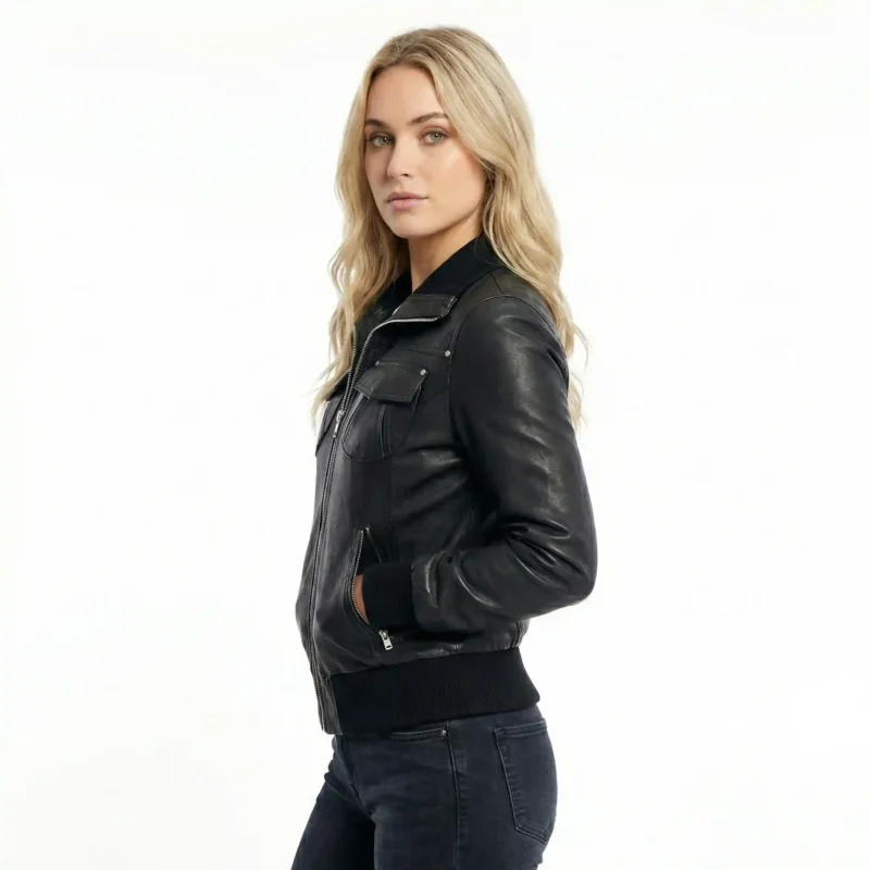 Side profile of Astra Prime black leather bomber jacket showing fitted silhouette, chest pocket detail, ribbed side panels, and hip-length cut