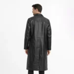 Rear view of black leather trench coat showing clean back panel, center vent, knee-length proportion, classic overcoat construction