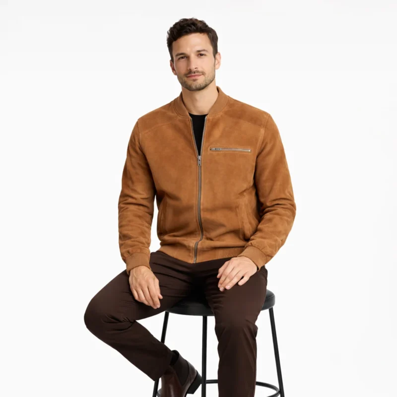 Man seated wearing tan camel suede bomber jacket showing comfortable fit, accessible pockets, natural nubuck draping, ribbed elements flexibility, and luxurious suede texture while sitting