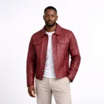 Front view of men's burgundy red leather trucker jacket with pointed collar, button-front closure, dual flap chest pockets with button tabs, vertical seaming, and classic denim-inspired design