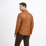 Rear view of tan cognac leather shirt jacket showing western yoke stitching across shoulders, smooth back panel, and curved shirt hem