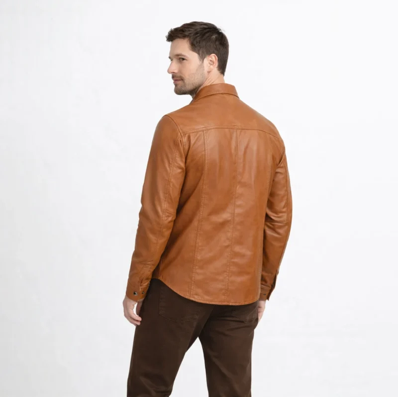 Rear view of tan cognac leather shirt jacket showing western yoke stitching across shoulders, smooth back panel, and curved shirt hem