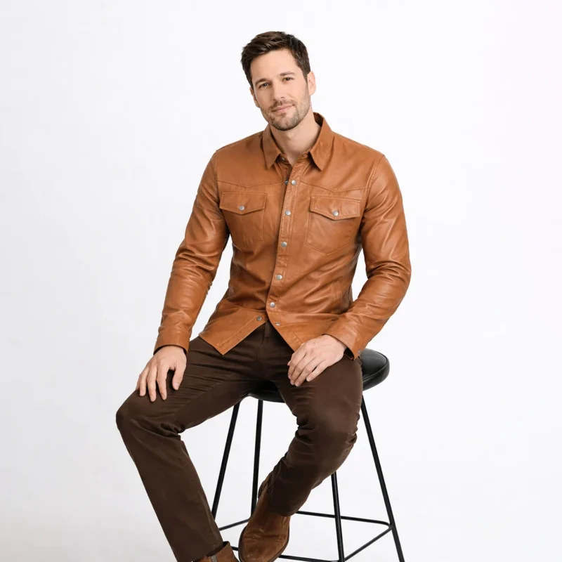 Man seated wearing tan cognac leather shirt jacket with dark brown pants, demonstrating comfort, flexibility, and maintained shape while sitting