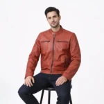 Man seated wearing terracotta orange leather cafe racer jacket showing comfortable fit, natural leather movement, pocket accessibility, and vibrant color in seated position