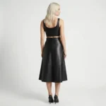 Back view of black leather midi skirt showing smooth drape, calf-length hem, and structured paneling on a female model - Imperial Noir Flare Skirt