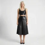 Front view of model wearing high-waisted black leather midi skirt with vertical panel seams and A-line silhouette against white background.