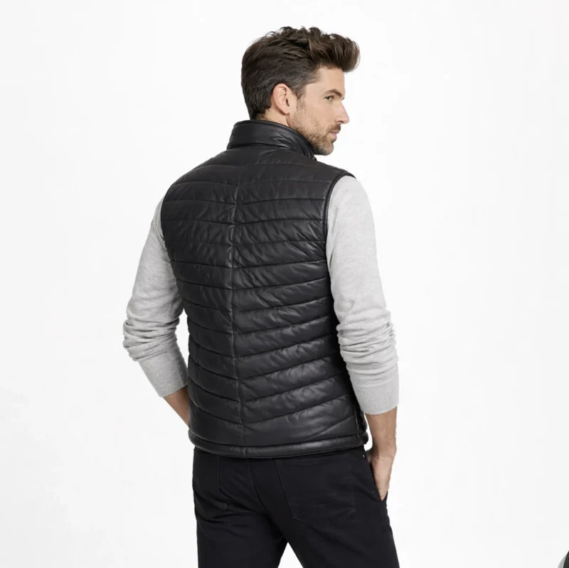 Rear view of black leather puffer vest showing horizontal quilted channels, clean back construction, stand collar, sleeveless design of Ironcrest Obsidian Leather Field Vest