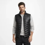 Front view of men's black leather puffer vest - Ironcrest Obsidian Leather Field Vest - with stand collar, central zipper, horizontal quilted channels, sleeveless design, lightweight insulation