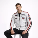 Man seated wearing white leather racing jacket with patches showing comfortable fit, visible racing stripes, accessible pockets, motorsport sponsor logos, and authentic vintage racing team styling