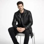 Man seated wearing black leather peacoat with black pants, demonstrating comfort, flexibility, and maintained structure while sitting