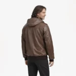 Side profile of brown leather hooded bomber jacket showing ribbed trim, epaulette detail, relaxed fit, and classic bomber silhouette