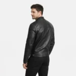 Rear view of black leather biker jacket showing quilted ribbed shoulder yoke, smooth leather back panel, quilted sleeves, center back seam, straight hem, and dramatic texture contrast