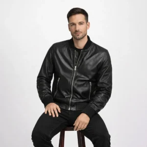 Man wearing black leather bomber jacket while seated, demonstrating comfortable fit, ribbed trim detail, and supple leather construction