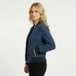 Side profile of navy suede bomber jacket showing ribbed collar and cuffs, zippered pocket, fitted feminine silhouette, luxurious nubuck finish of Noir Vantique Leather Bomber Jacket