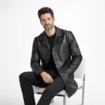 Seated profile of man in black leather car coat showing mid thigh length straight cut and notch collar detail - Obsidian Regent Leather Coat