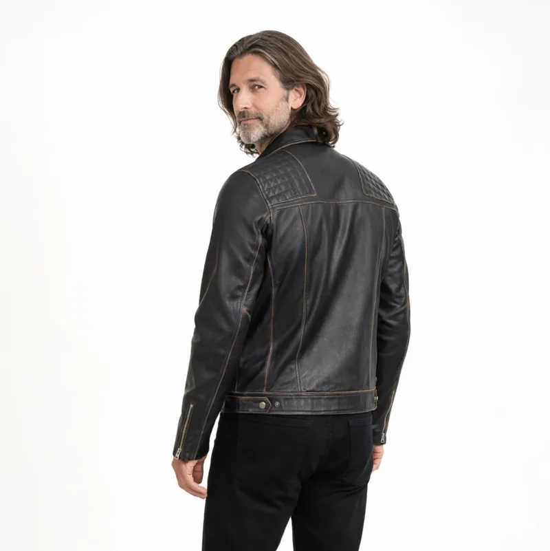Rear view of distressed black leather biker jacket showing smooth back panel, brass zipper accents on sleeves, and vintage finish with brown undertones