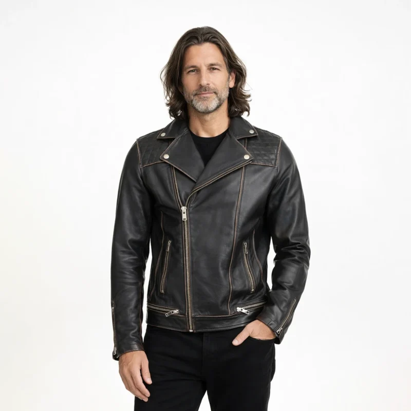 Man wearing distressed black leather motorcycle jacket with asymmetric brass zipper closure, wide lapel collar, multiple zip pockets, and vintage hardware on light background