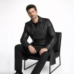 Seated profile of man in black leather trench coat showing knee length cut belted waist and structured shoulders - Onyx Vanguar Luxury Leather Trench Coat