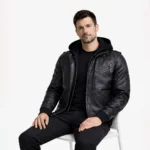 Man seated wearing black leather bomber jacket with hood showing comfortable fit, removable hood feature, practical everyday wear