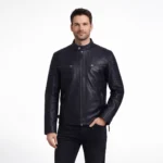 Man wearing black leather motorcycle jacket with stand collar, center zip closure, ribbed shoulder panels, horizontal chest zip pockets, and black jeans on light gray background