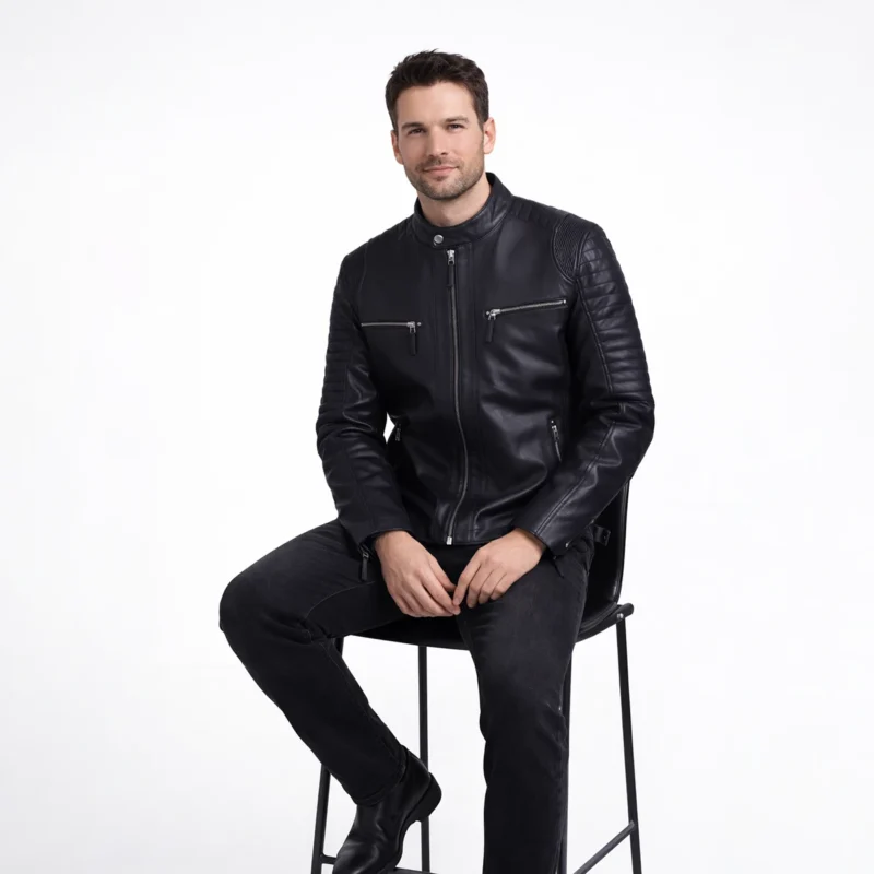 Man seated wearing black leather motorcycle jacket with black jeans, demonstrating comfort, flexibility, and maintained structure while sitting