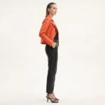 Side profile of woman in orange quilted leather biker jacket - Urban Dynasty Leather Jacket - showing diamond pattern stitching and fitted silhouette