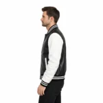 Side profile of black and white varsity jacket showing leather body, white sleeve, striped ribbed trim, and classic athletic silhouette