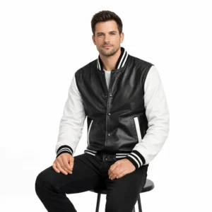 Man wearing black and white varsity jacket while seated, demonstrating comfortable fit and classic letterman styling