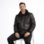 Man seated wearing black leather aviator jacket showing comfortable fit, luxurious fur collar, functional chest pockets, practical cold weather wear