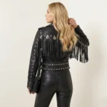 Woman wearing black studded fringe leather jacket styled with black leather straight-leg pants and black handbag for bold complete outfit of Women’s Studded Biker Fringe Jacket