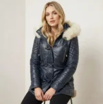 Woman wearing navy leather parka with fur trimmed hood, quilted sleeves and toggle closure, front view