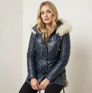 Woman wearing navy leather parka with fur trimmed hood, quilted sleeves and toggle closure, front view