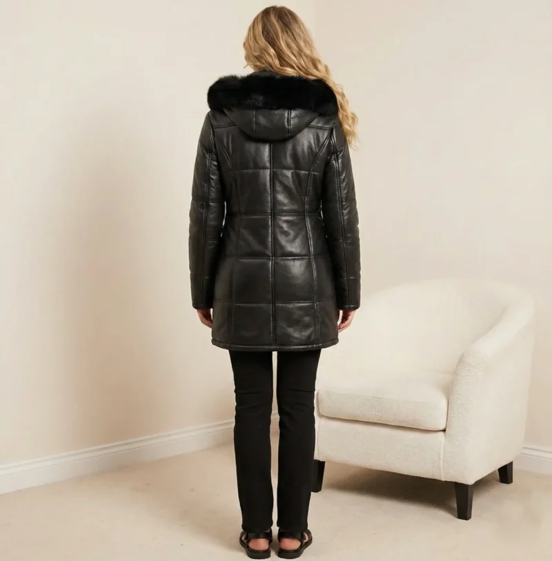 Back view of women’s black leather coat with attached fur hood and fitted silhouette