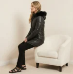 Side view of black leather winter coat with fur hood showing fitted waist and zip closure